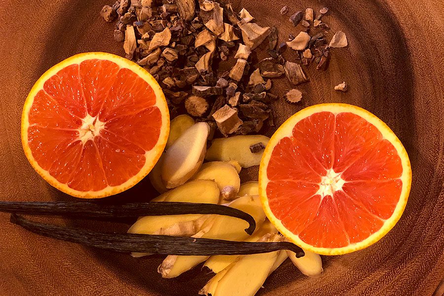 A wooden bowl filled with fruit and spices.