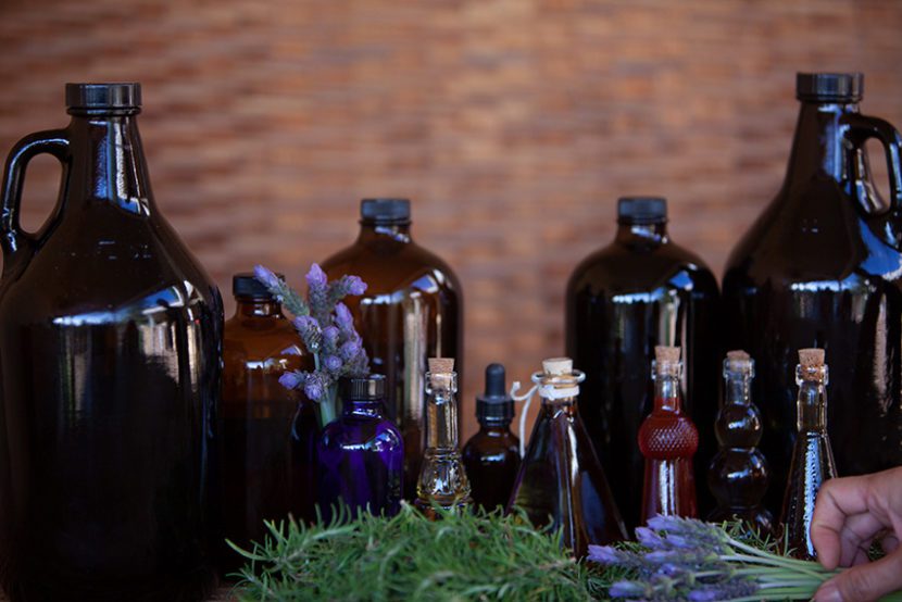 A table with several bottles of oils and lavender.