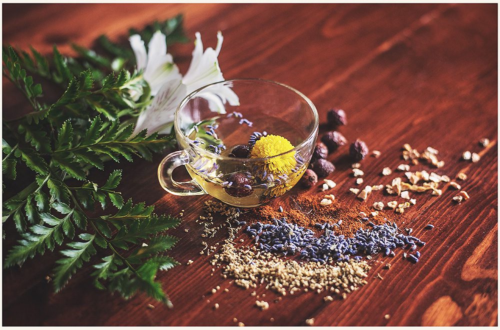 A cup of tea with some lavender and other ingredients on the table.