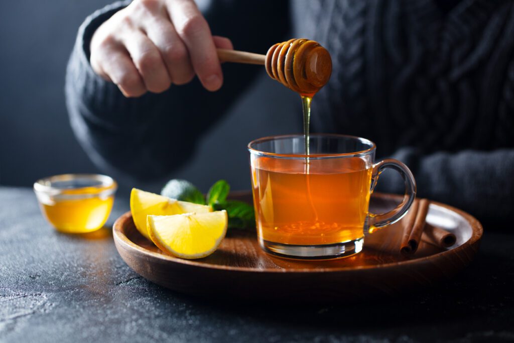 A person is pouring honey into a cup.