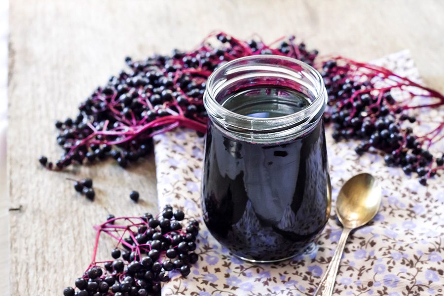 A jar of elderberry syrup on top of a table.