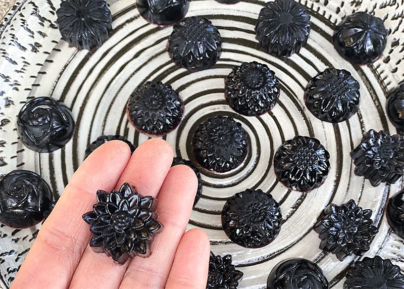 A hand holding a black flower shaped candy.