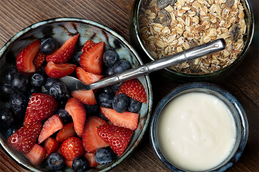 A bowl of strawberries, blueberries and granola with yogurt.