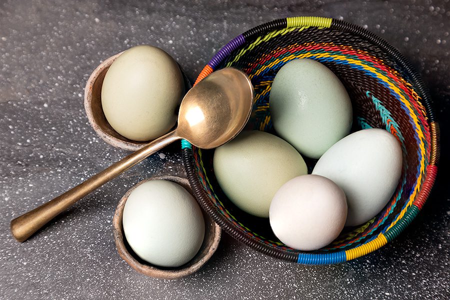 A basket of eggs and spoons on the ground.