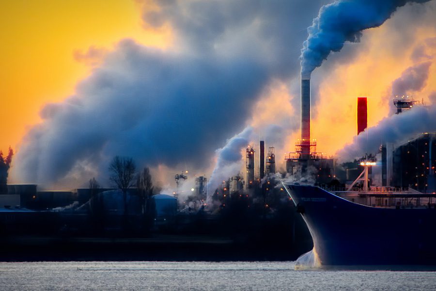 A ship is in the water near some factories.