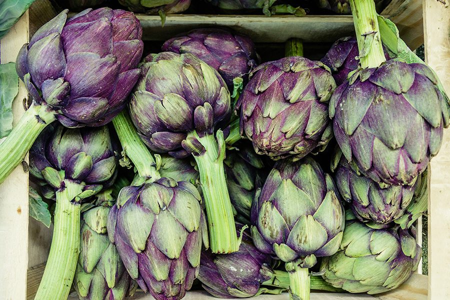 A pile of purple artichokes sitting on top of each other.