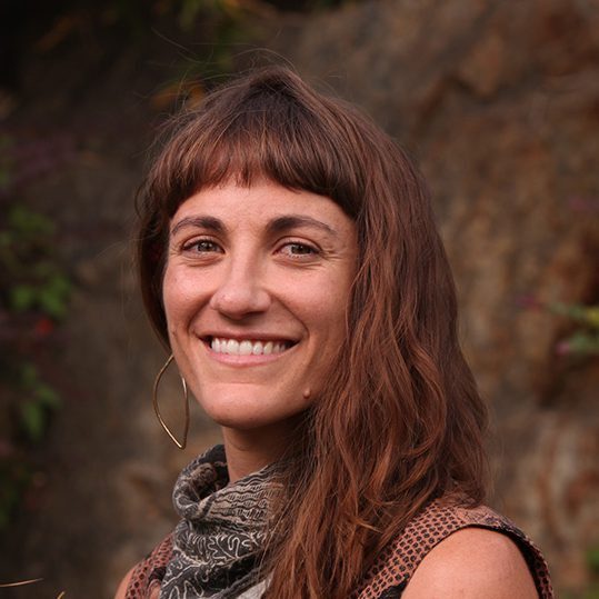 A woman with long hair and a scarf smiles for the camera.