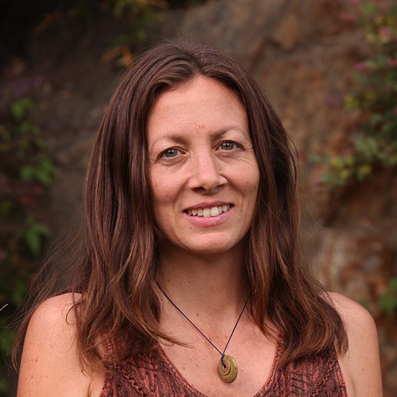 A woman with long hair wearing a brown top.